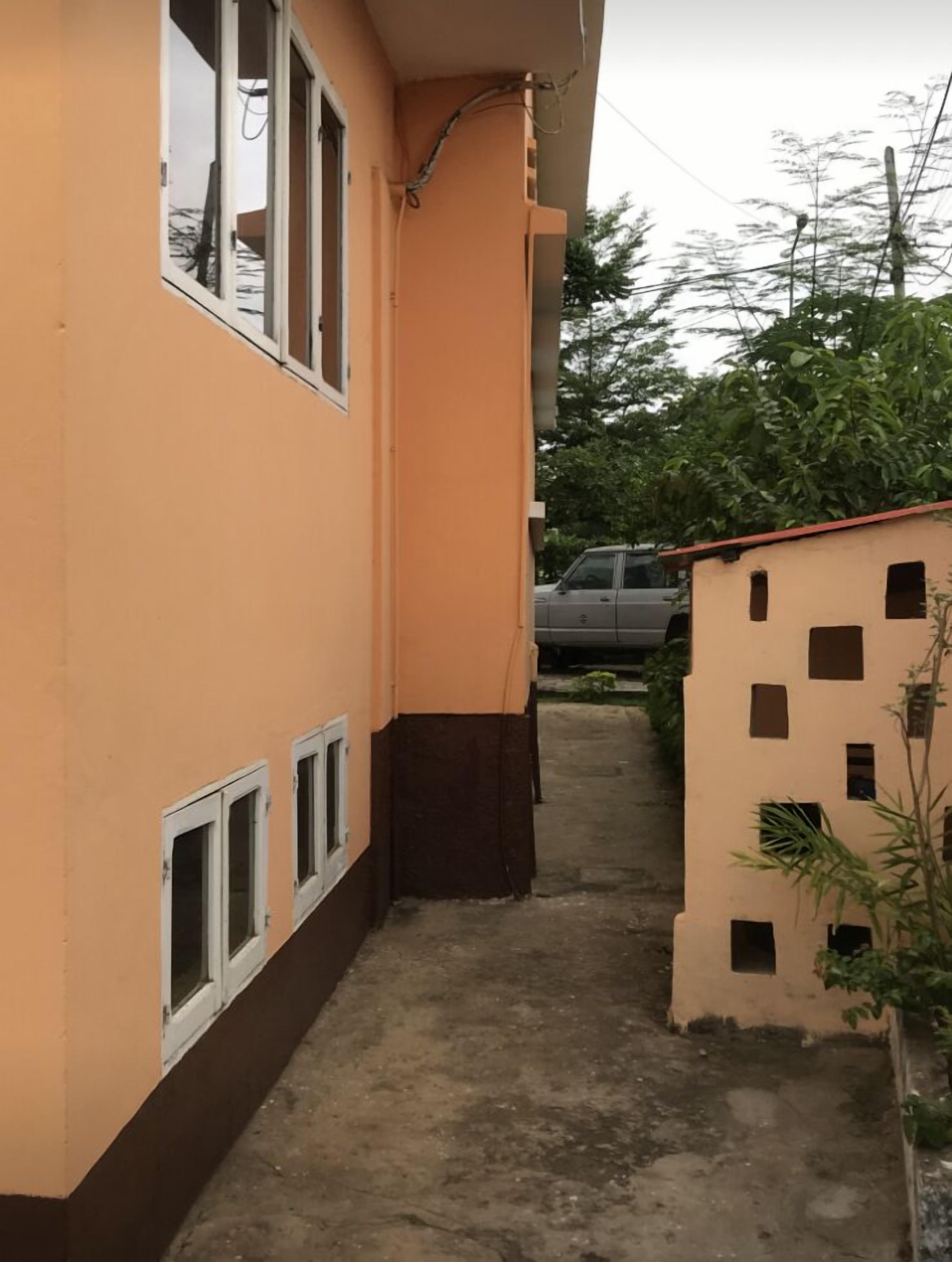 Une ruelle étroite, située entre deux immeubles, avec une voiture garée au fond.