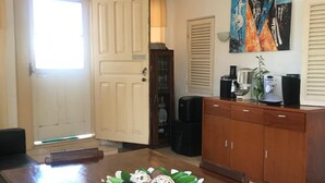 Un coin repas avec une table en bois, des chaises, un élément décoratif au centre, une machine à café et un tableau au mur.
