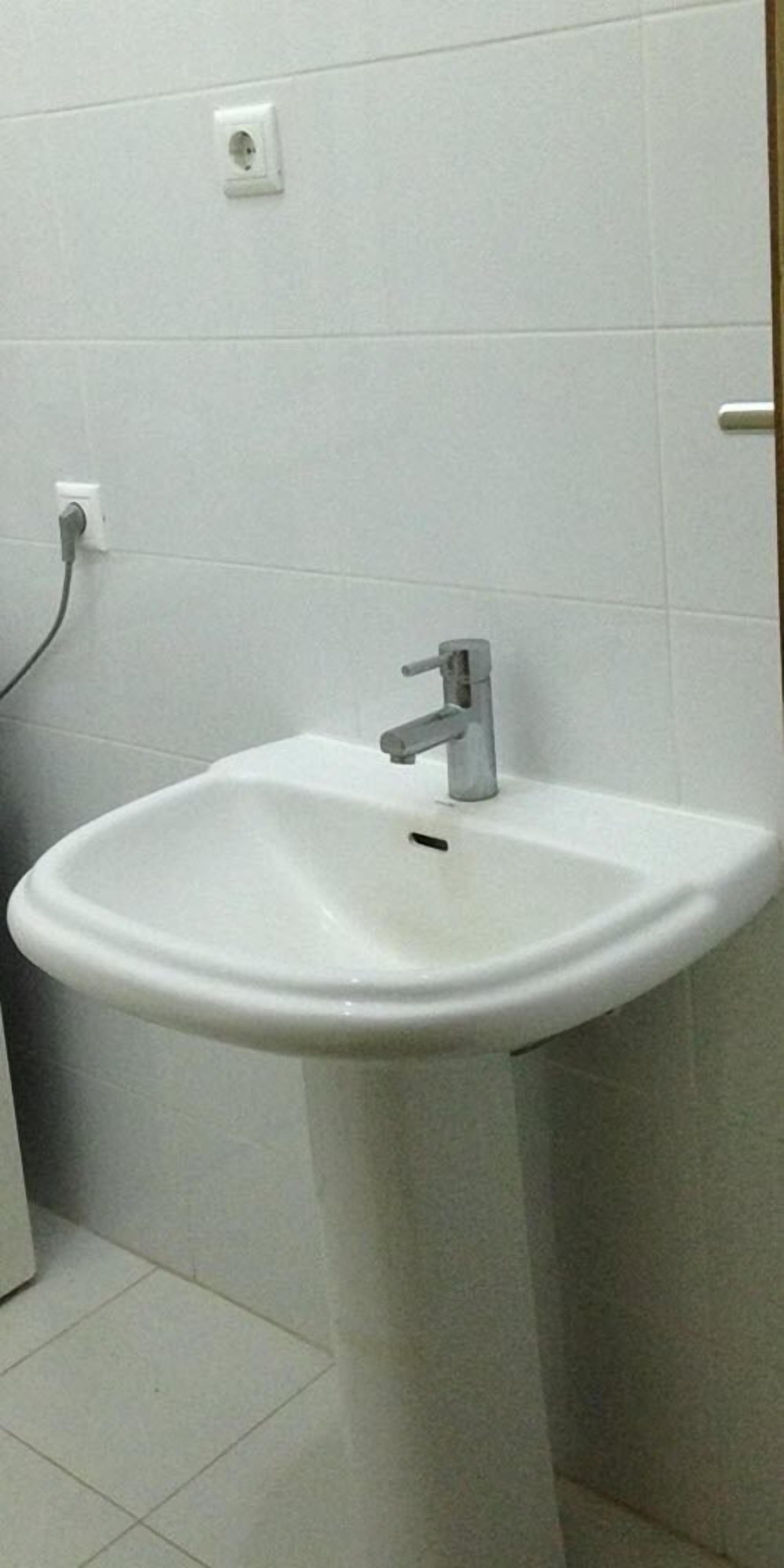 Un llei blanc amb un sol vàlvula en un bany de parets i terra emblaquenats.