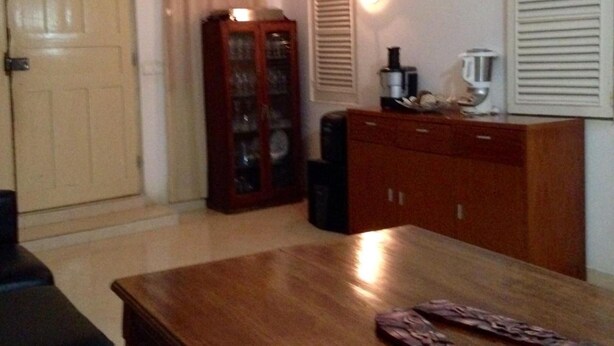 Une pièce avec une table en bois, une armoire, une porte et une fenêtre avec des volets.