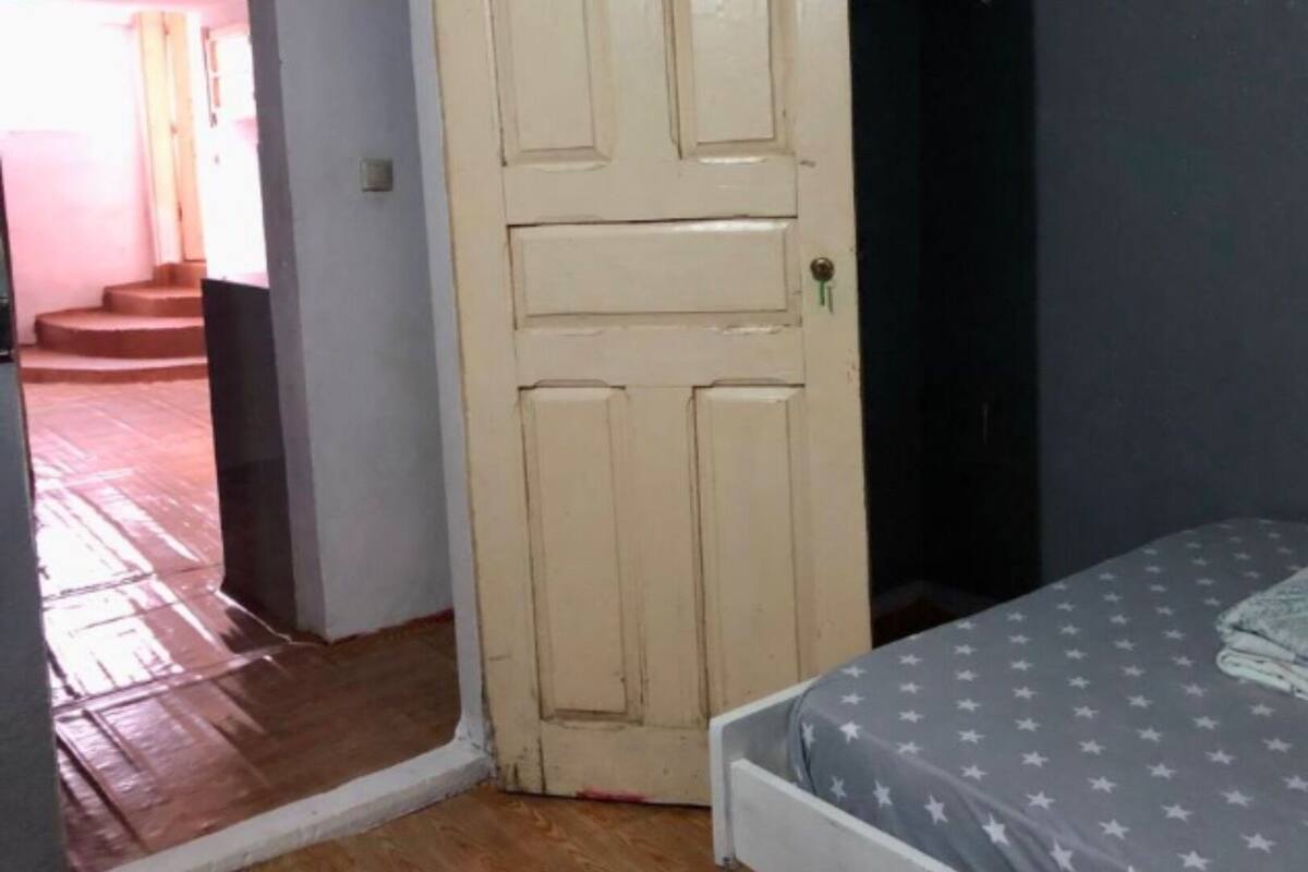 Een slaapkamer met een bed, een deur en een trap die naar een buitenruimte leidt.