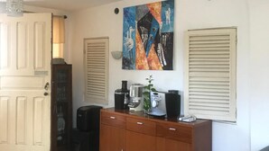 Une pièce avec un meuble en bois, une machine à café, une plante et un tableau accroché au mur.