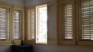 Une chambre à coucher avec un lit, une table de chevet et une fenêtre avec des volets.