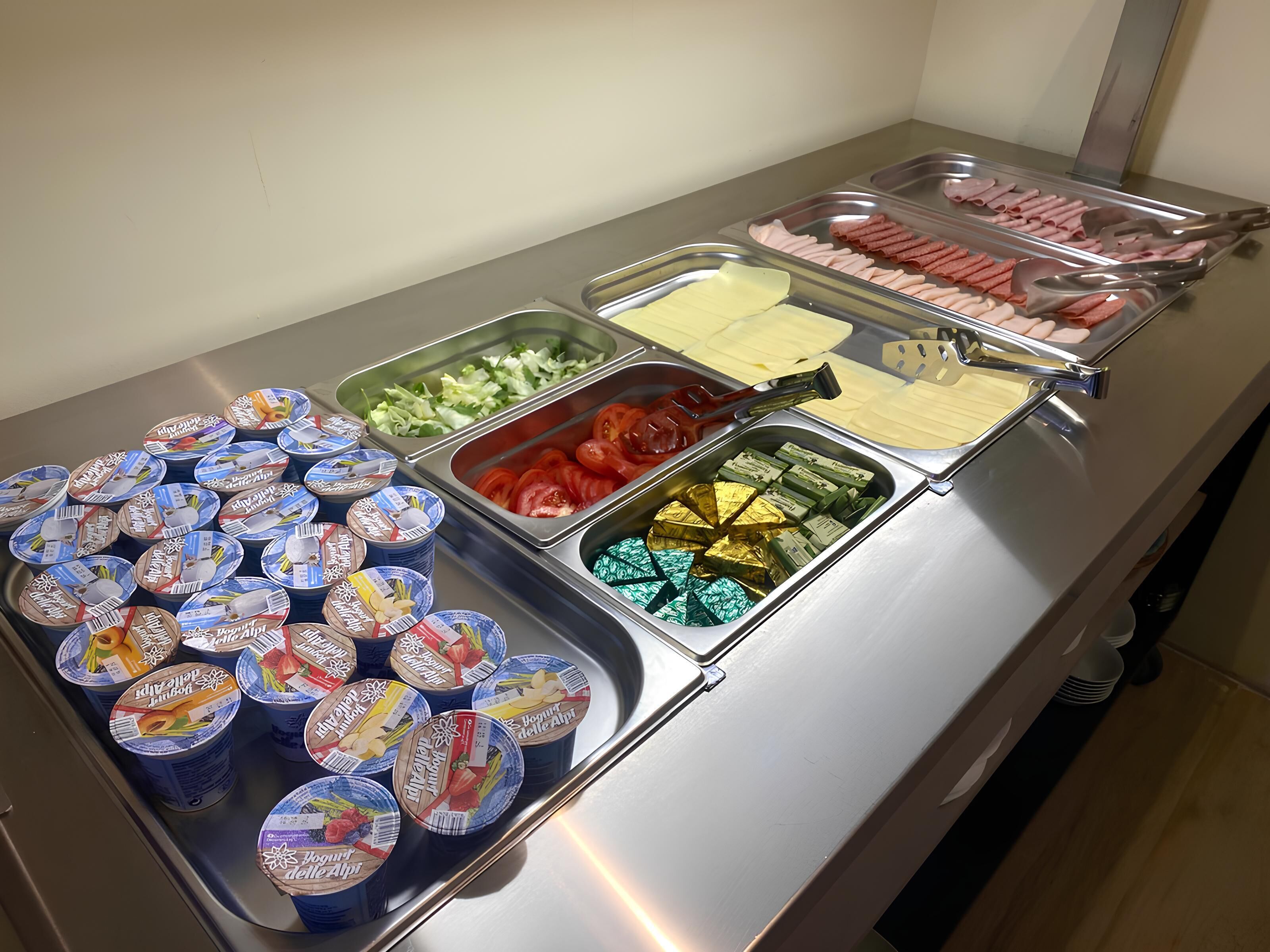 A buffet with various food items including yogurt, vegetables, and meat.