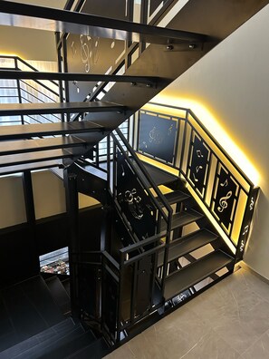 A modern staircase with a metal railing and a decorative wall panel featuring musical notes.