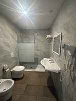 Un baño moderno con ducha, inodoro, bidé y lavamanos.