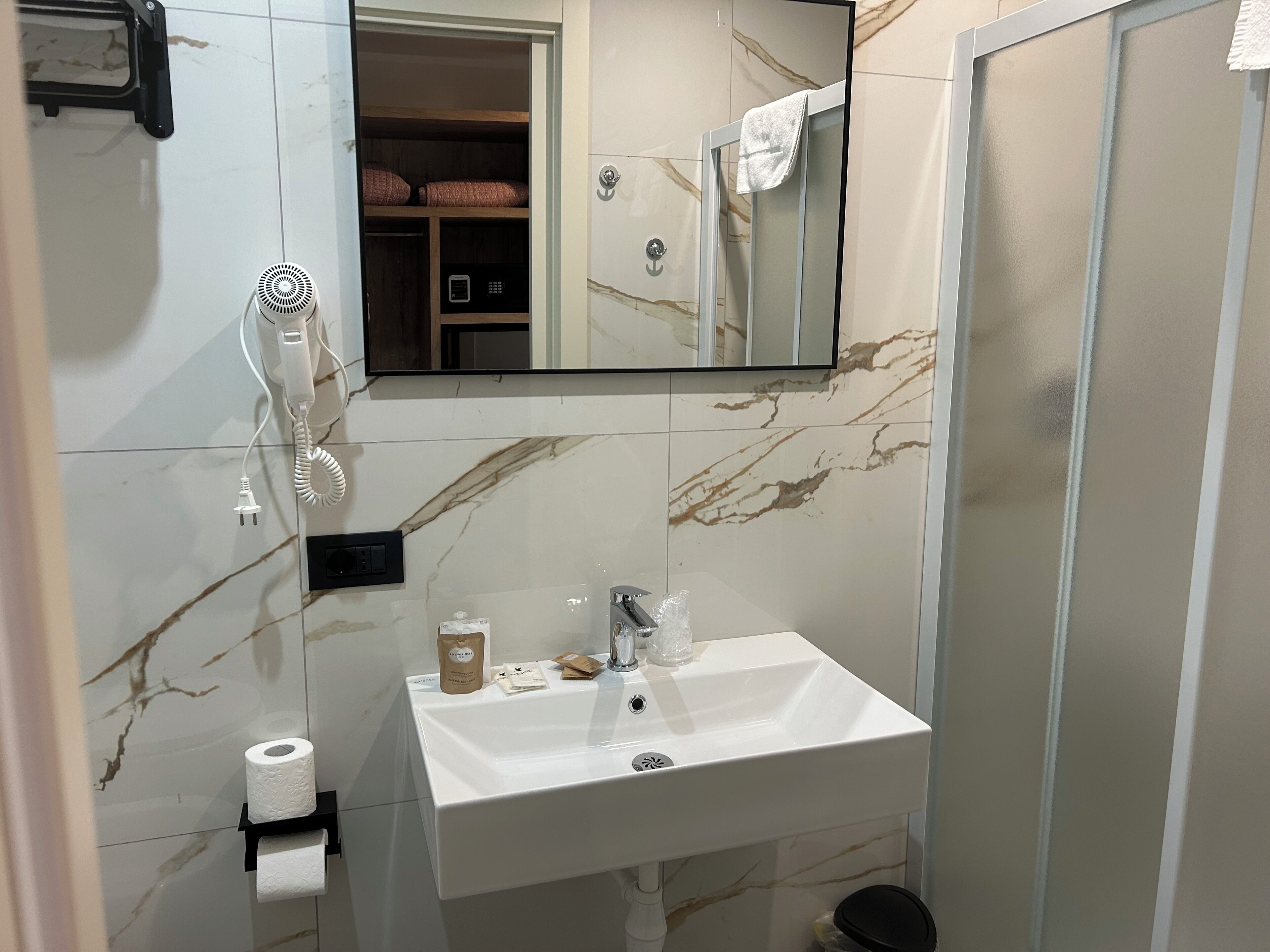 A bathroom with a white sink, a mirror, a towel rack, and a shower area.