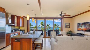 A modern kitchen with a central island, bar stools, and a large window overlooking the ocean. - The Beach Villas at Ko Olina by Real Select Vacations (Kapolei)