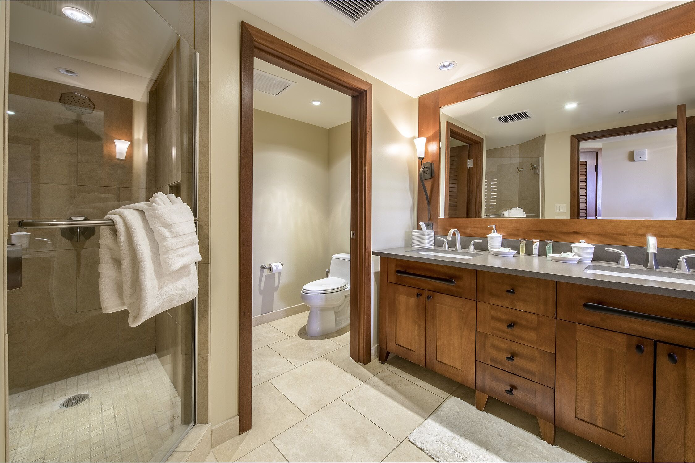 A modern bathroom with a glass-enclosed shower, wooden cabinets, and a large mirror.