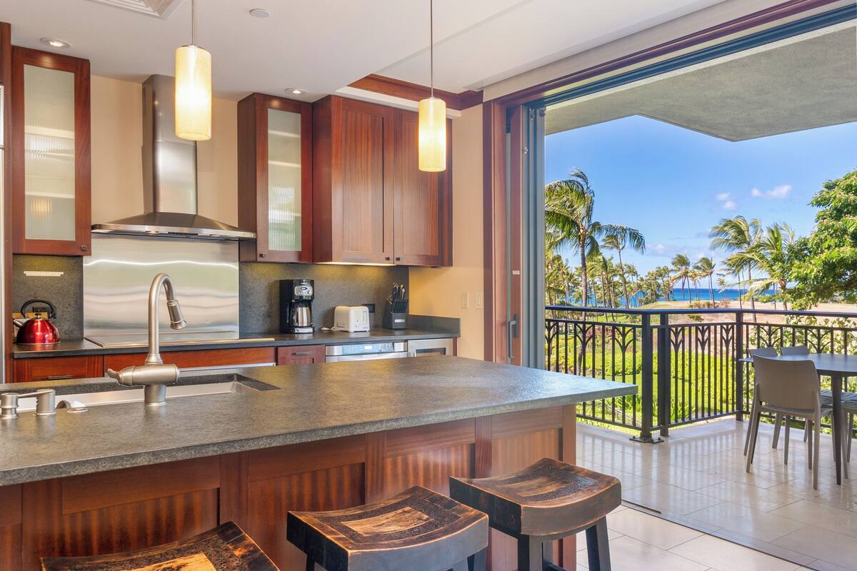 Una cocina moderna con una isla grande, electrodomésticos de acero inoxidable y vistas al océano.
