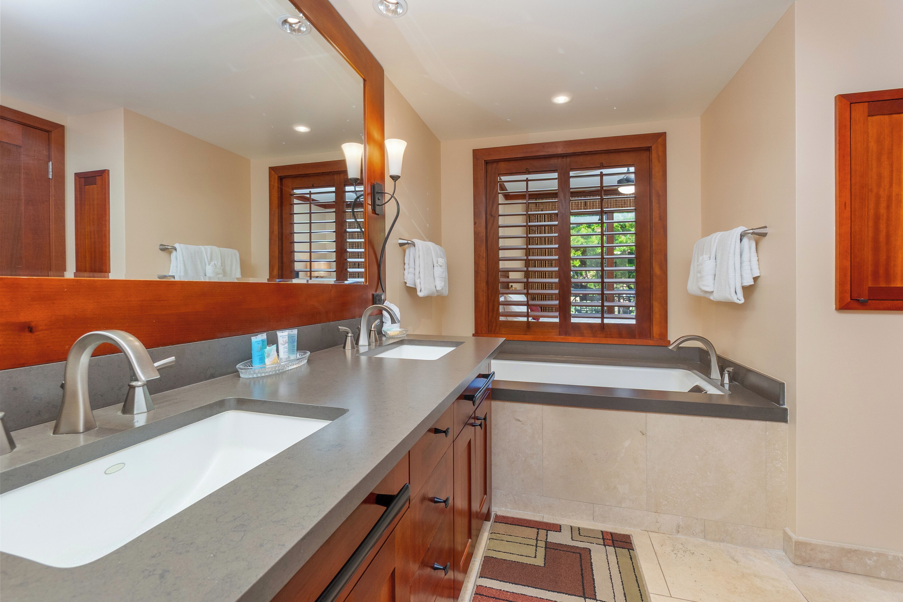 A modern bathroom with two sinks, a large mirror, and wooden accents.