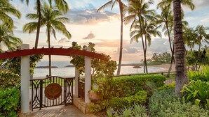 A coastal garden with a pergola, palm trees, and a view of the sea. - The Beach Villas at Ko Olina by Real Select Vacations (Kapolei)