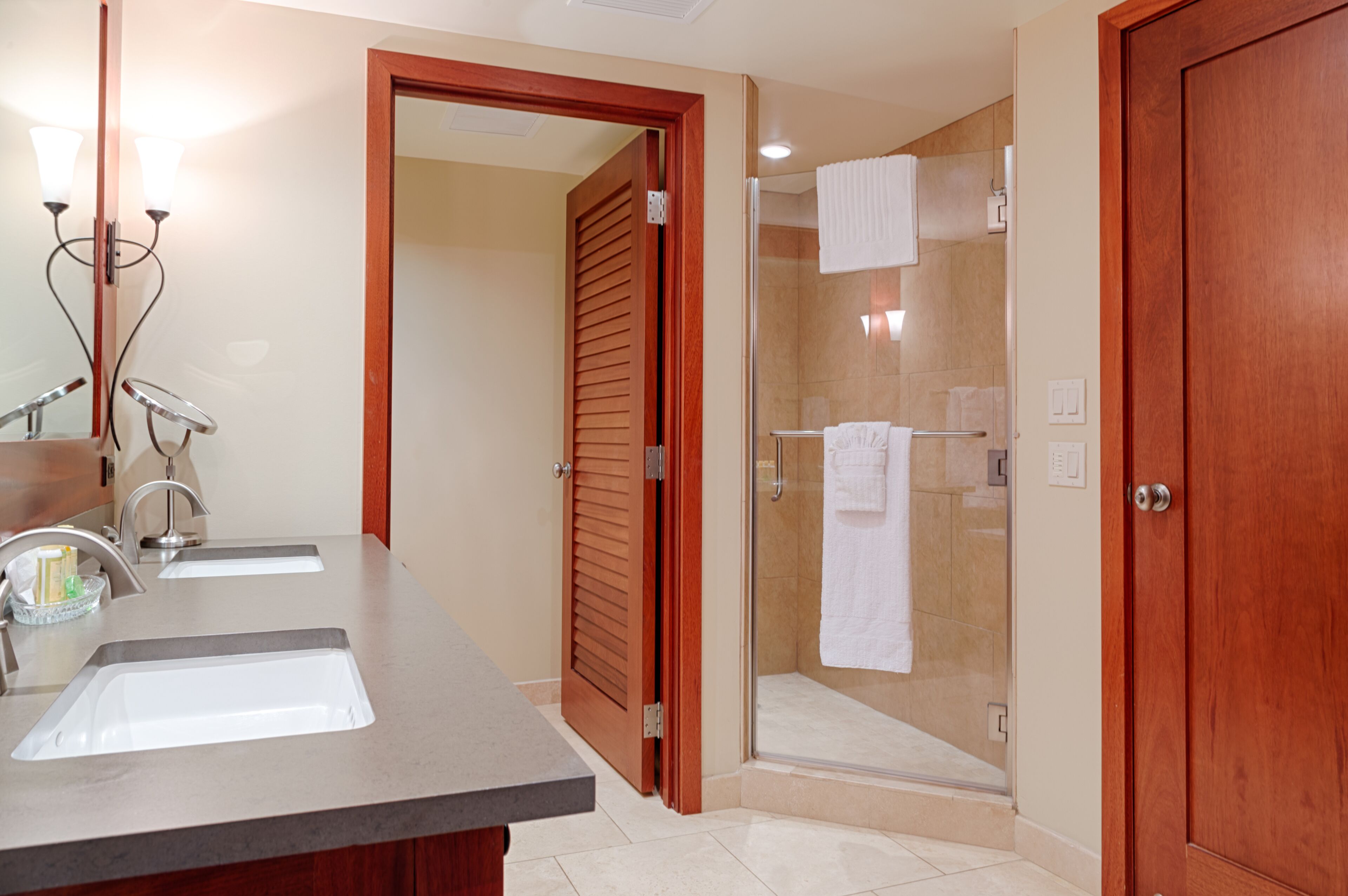 A bathroom with two sinks, a glass shower enclosure, and a wooden door.