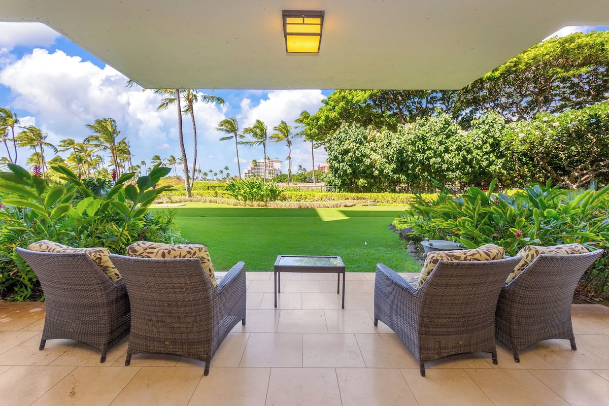 Un patio con muebles de mimbre y vista a un campo de golf.