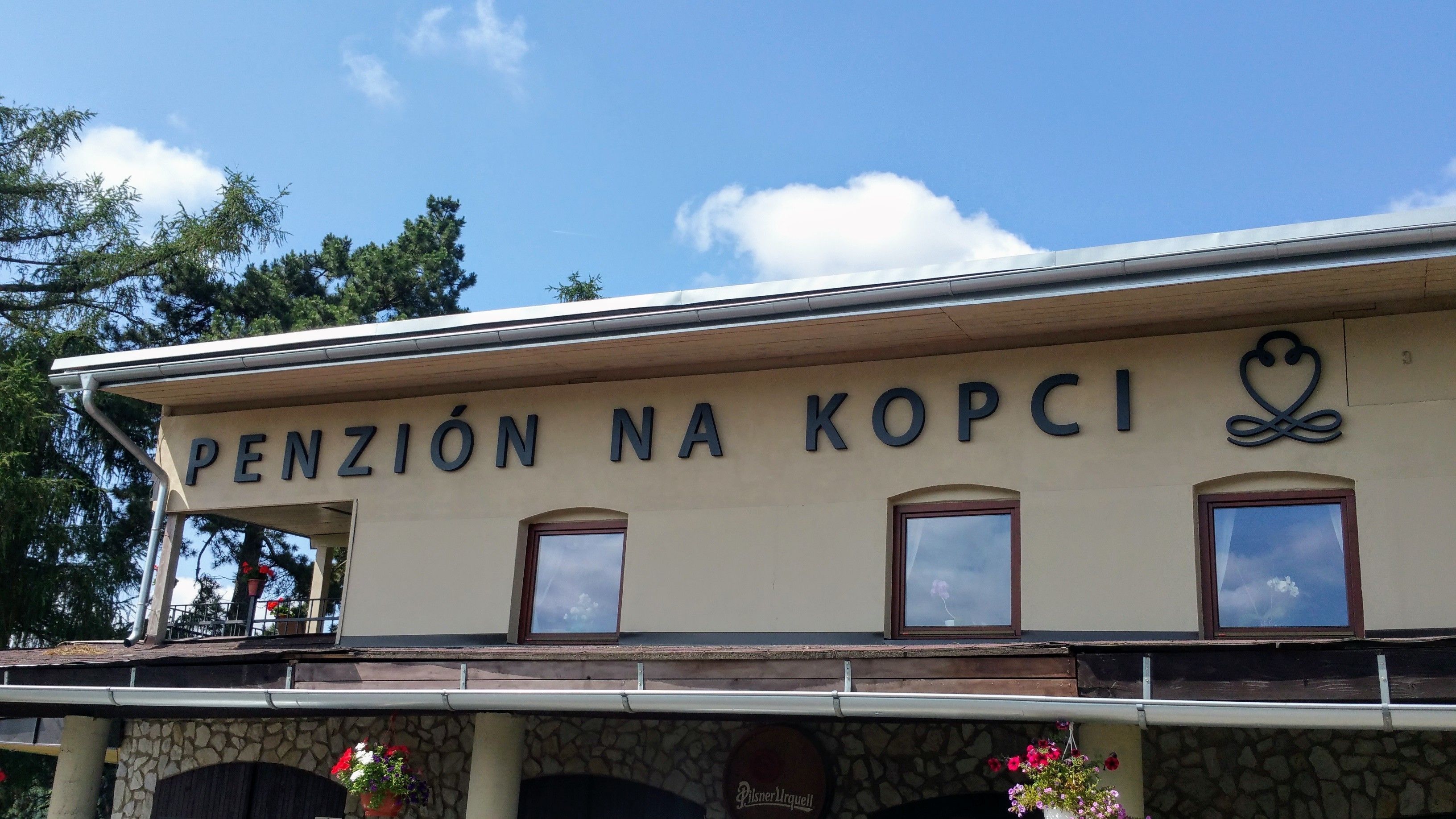 Un edificio con el letrero "PENZIÓN NA KOPCI" y fachada de piedra.
