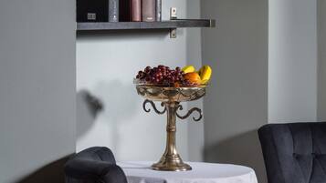 Ein Tisch mit Obstschale, ein Stuhl und ein Bücherregal an einer Wand.