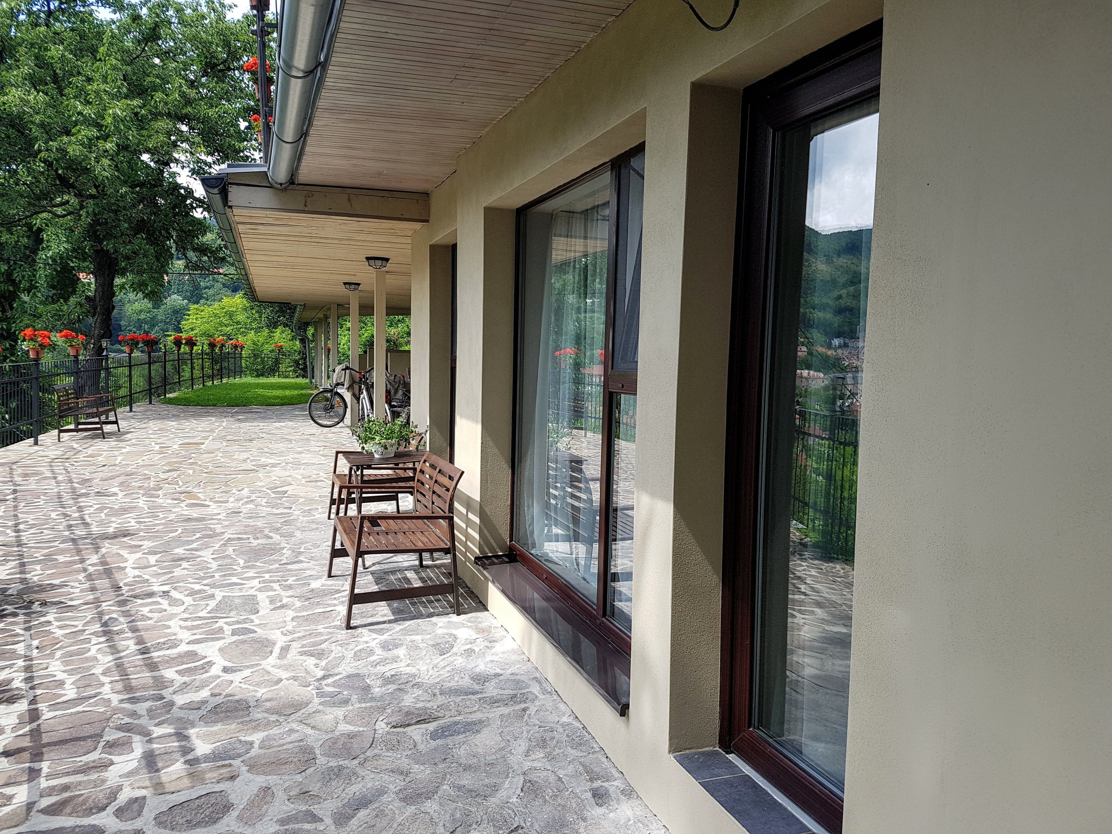 A covered outdoor seating area with stone flooring, a bench, and a table.