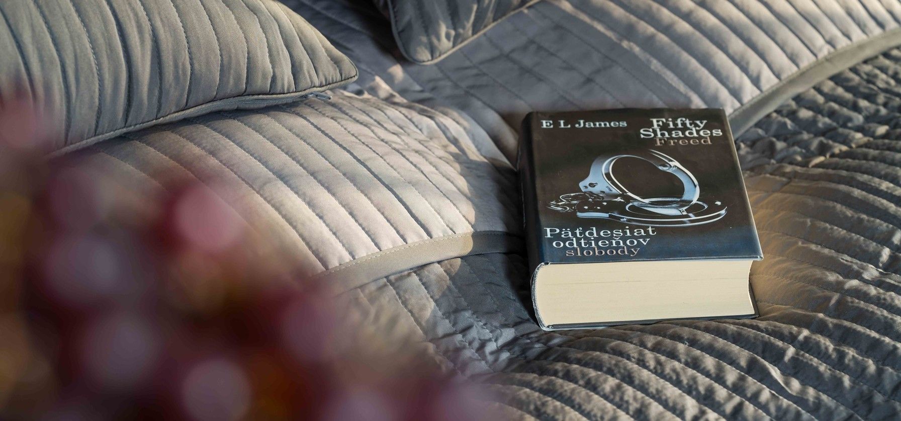 Un libro titulado “Fifty Shades Freed” sobre una cama con cubierta acolchada.