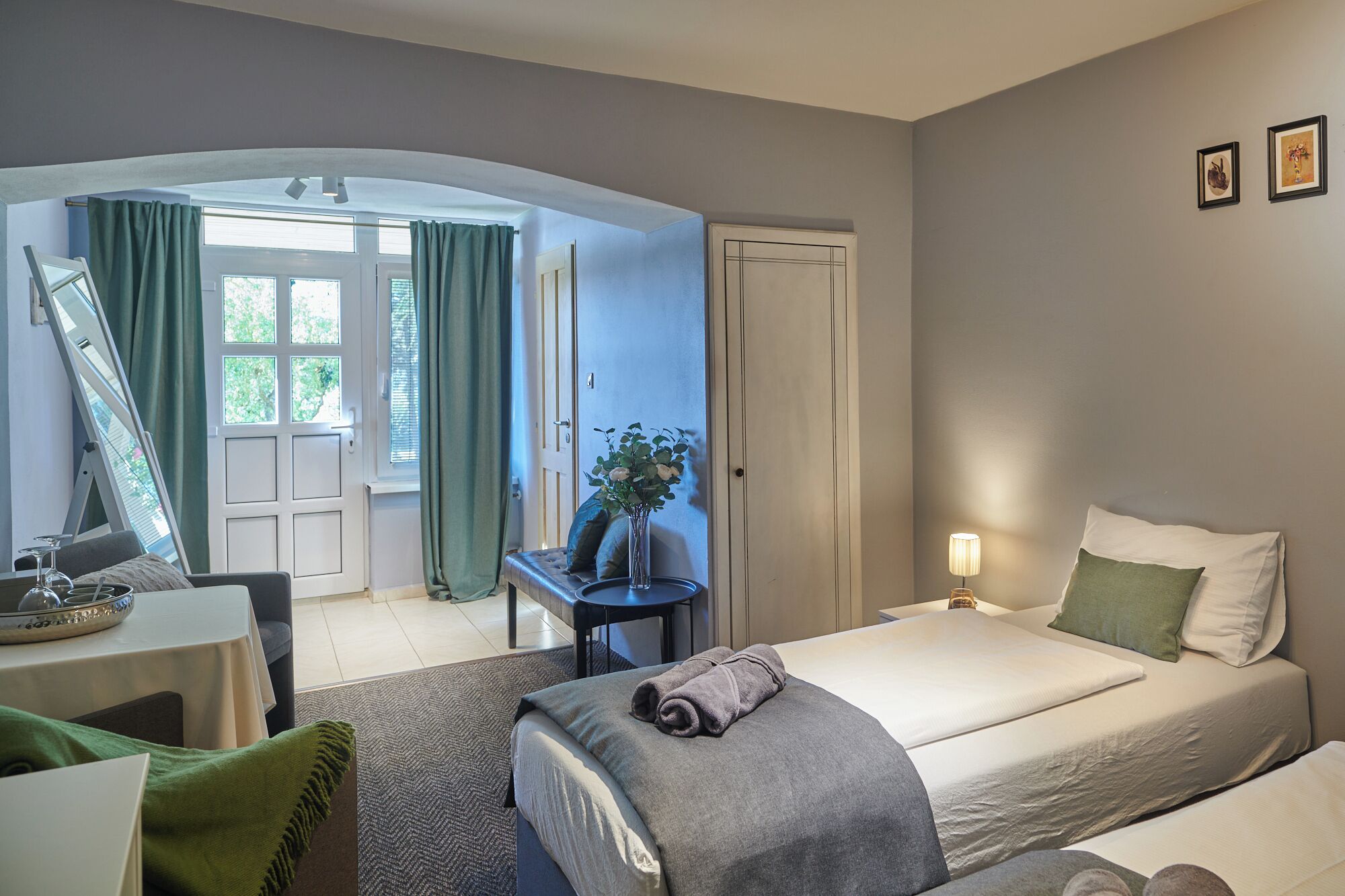 Una habitación de hotel con cama, escritorio, silla, espejo y ventana con cortinas.