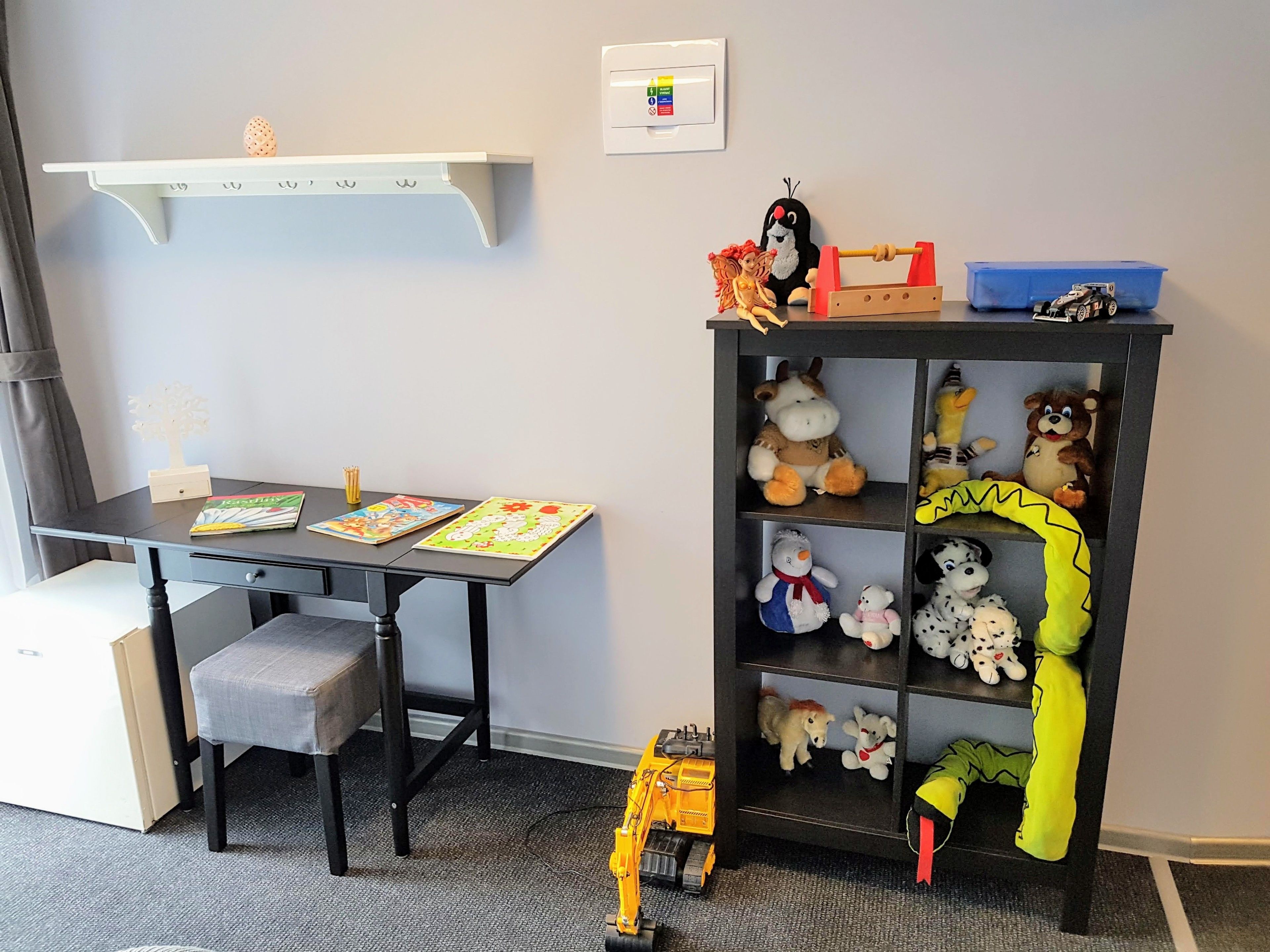 Un área de juegos para niños con escritorio, silla y un excavador de juguete.