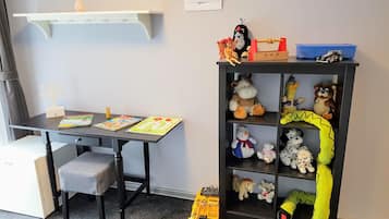 Un área de juegos para niños con escritorio, silla y un excavador de juguete.