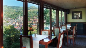 Comedor con ventanas amplias que ofrecen vistas a un pueblo y colinas.