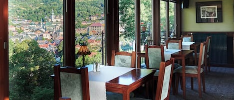 Comedor con ventanas amplias que ofrecen vistas a un pueblo y colinas.