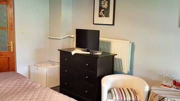 A bedroom with a bed, a dresser, a chair, a table with glasses, and a framed picture on the wall.