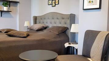 A bedroom with a bed, a chair, a small table, and wall decorations.