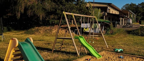 Un parque infantil con columpios y toboganes, rodeado de arena y juguetes.