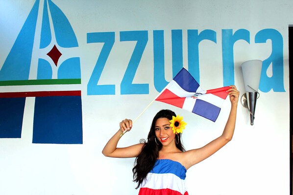 A person holding a flag in front of a wall with the text "P. Azurra".