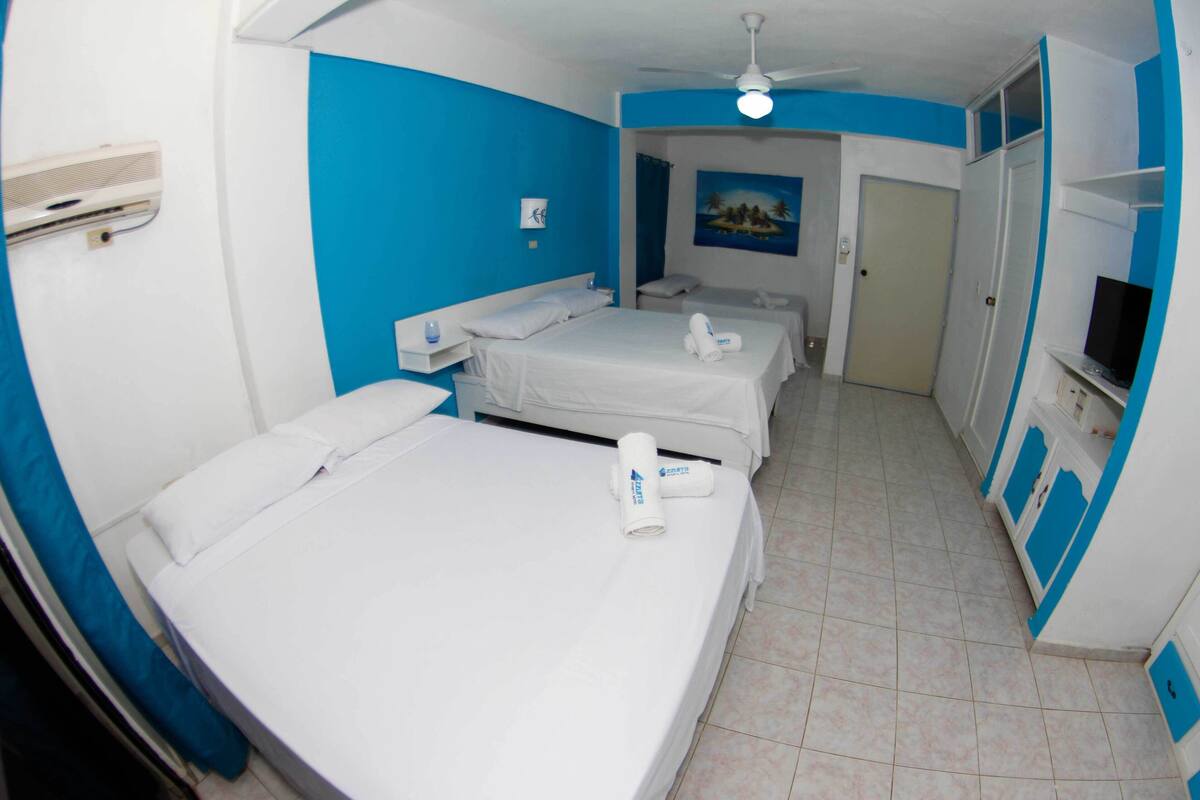 Une chambre d’hôtel avec deux lits, une télévision et un ventilateur de plafond.