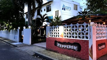 Un bâtiment blanc avec une enseigne indiquant « Pepperon » et « Parillada » sur le côté.