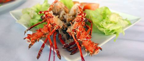 Une assiette de crabe cuit, accompagnée de laitue et d’une tranche de tomate.