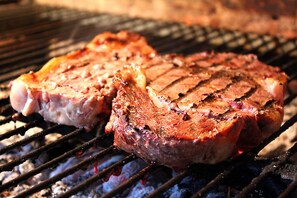 Two steaks being grilled on a barbecue.