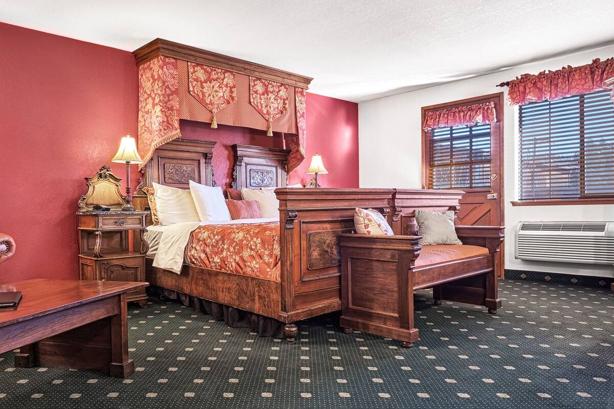Een klassieke kamer met een hemelbed, een houten bureau en een stoel.