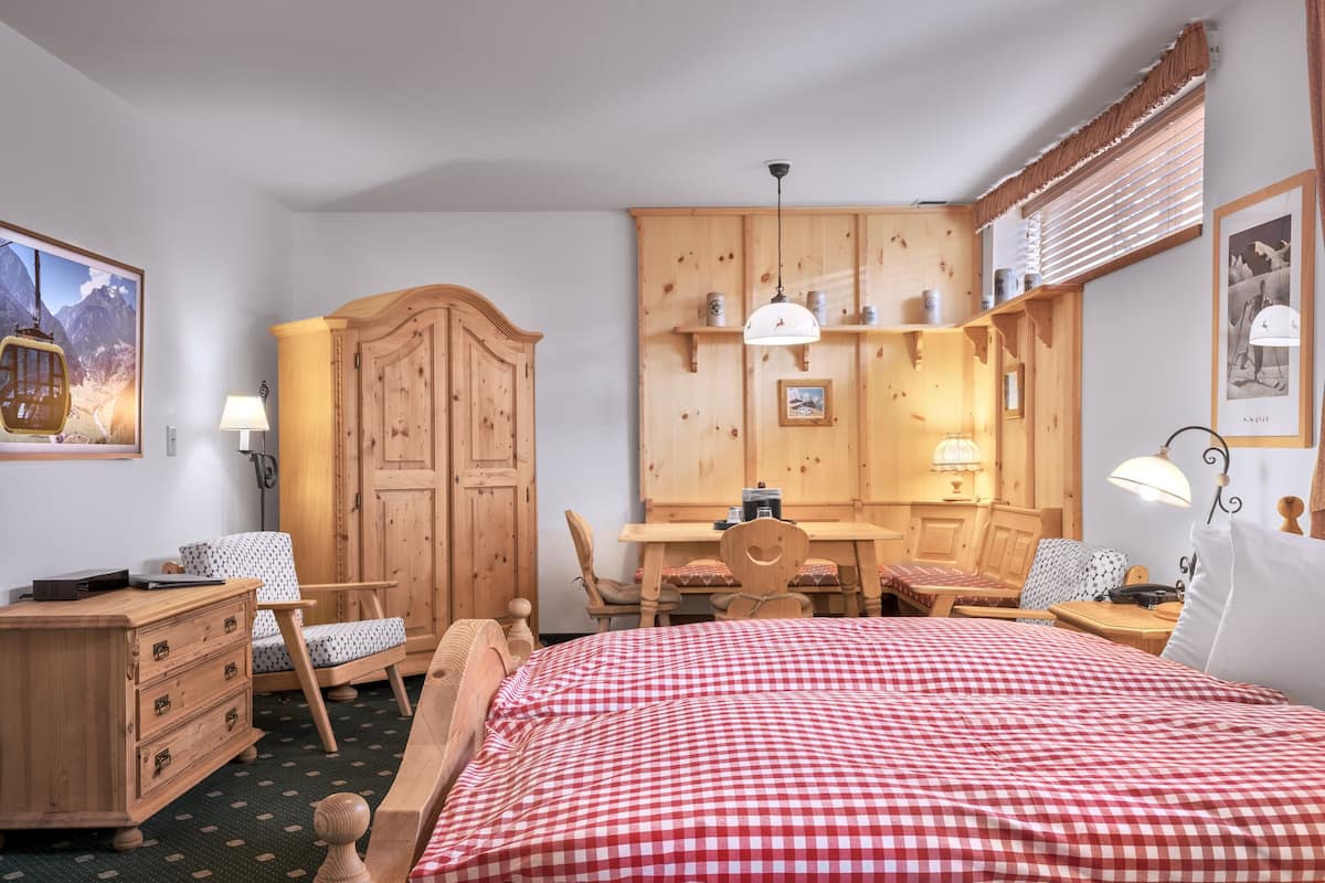 Een kamer met een bed, houten meubels, een bureau en een eethoek.