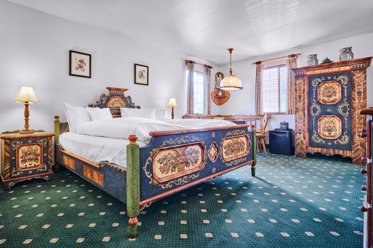 Een klassieke kamer met een bed, twee nachtkastjes, een kaptafel en een raam met gordijnen.