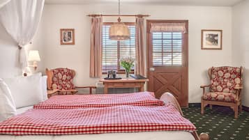Ein Hotelzimmer mit einem Bett, zwei Stühlen, einem Schreibtisch, einer Lampe, einem Vorhangfenster und einer Tür.