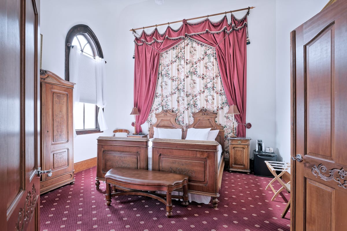 Een slaapkamer met een houten bed, een bankje, een kaptafel en een radiator.
