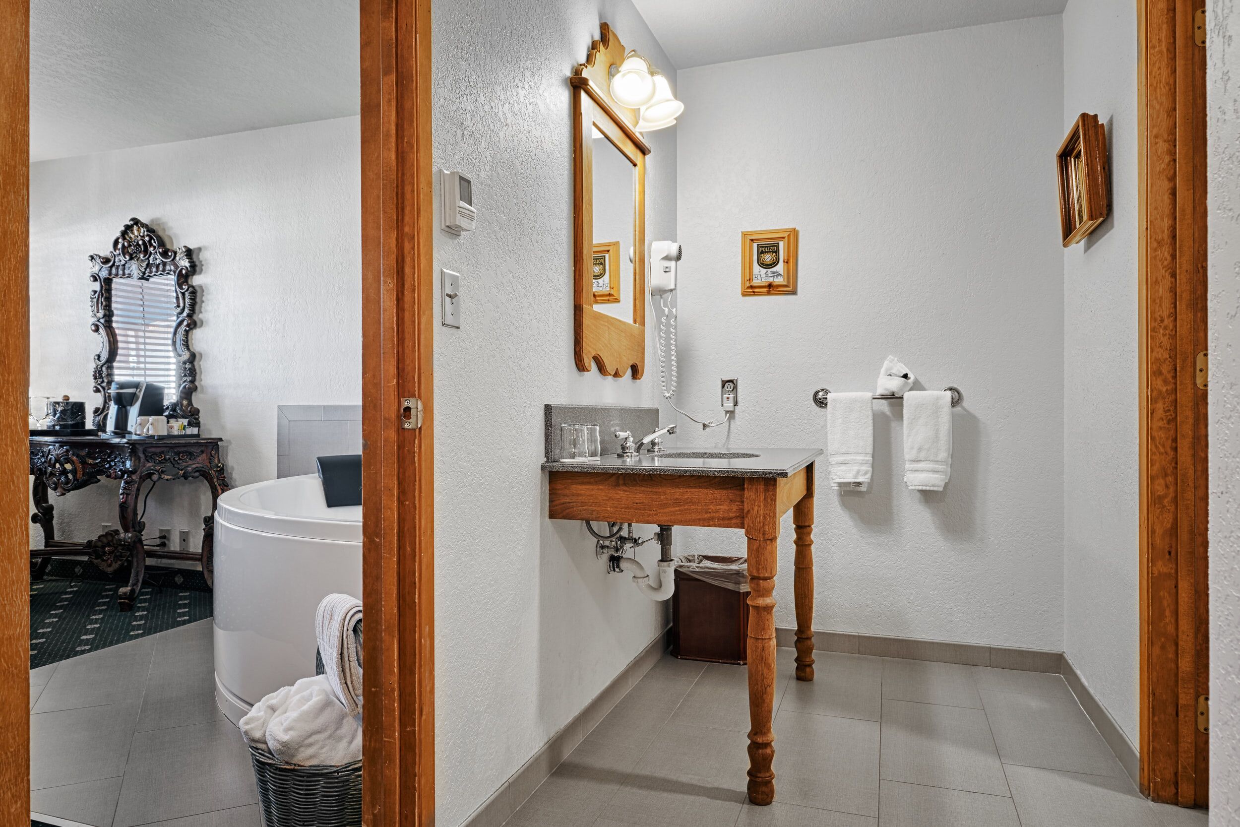 A bathroom with a wooden vanity, a large mirror, a bathtub, and a toilet.