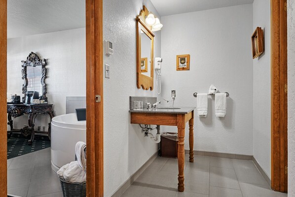 Un baño con tocador de madera, un espejo grande, una bañera y un inodoro.