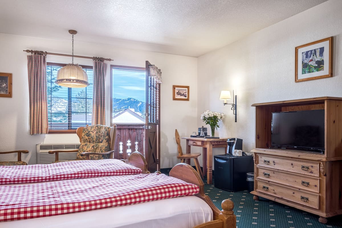 Een hotelkamer met twee bedden, een bureau met lamp, een televisie en een dressoir.