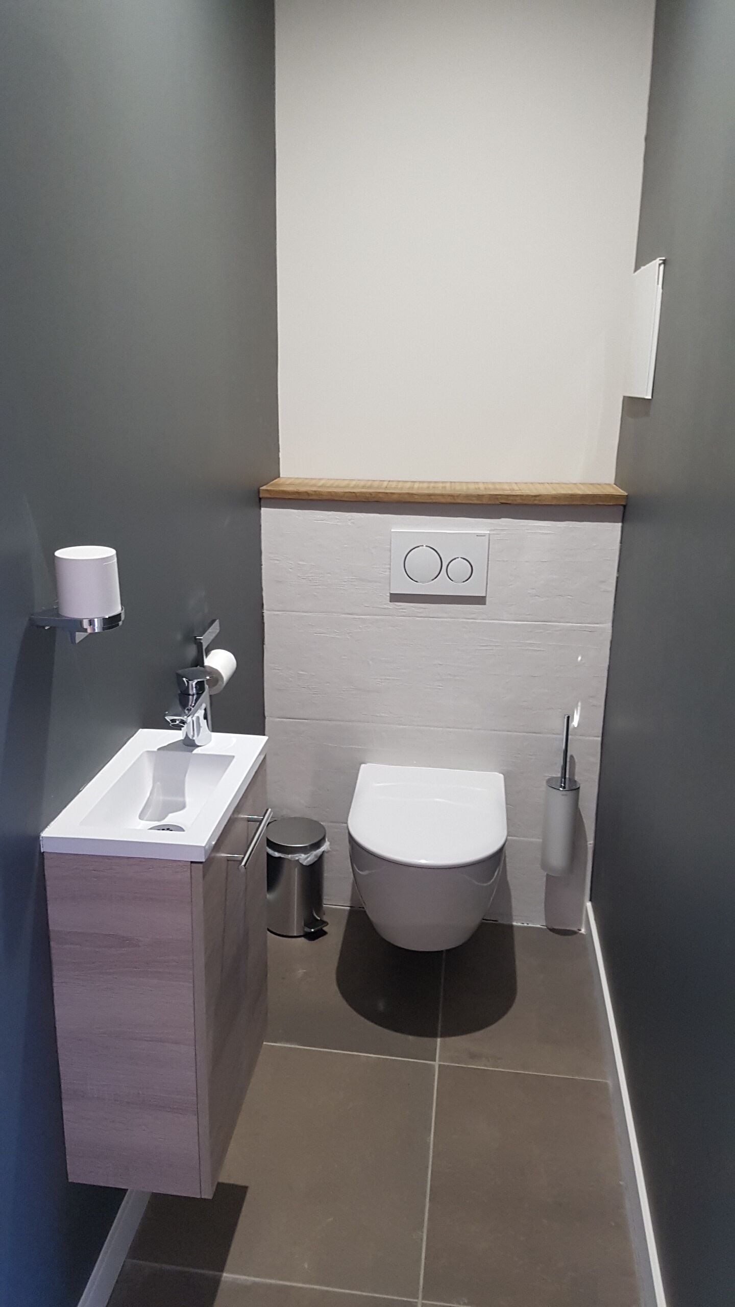 Un baño moderno con un lavamanos blanco, inodoro y un cubo de basura.