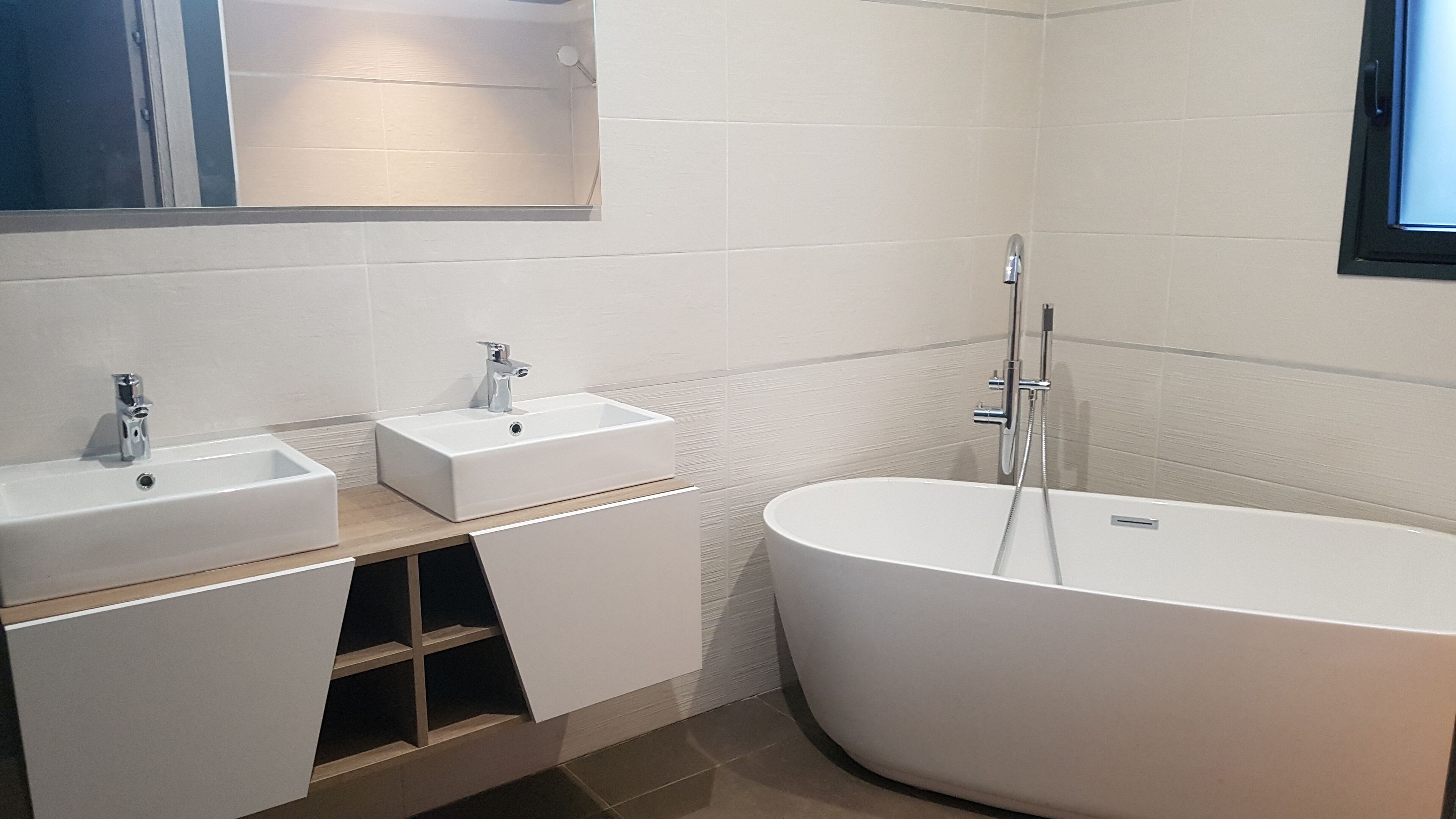 Een moderne badkamer met twee wastafels, een bad en een spiegel.
