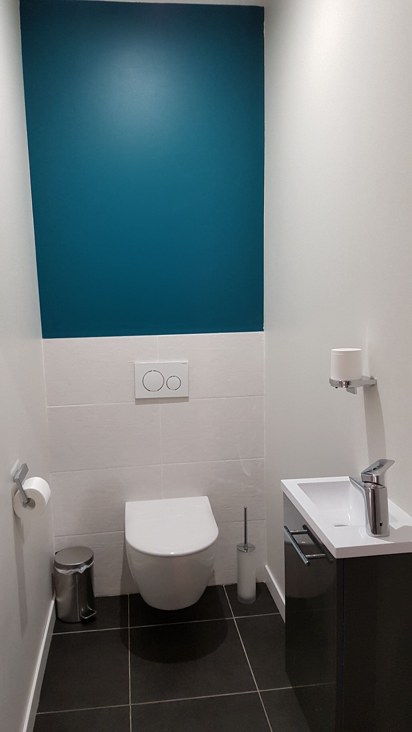 Ein modernes Badezimmer mit Toilette, Waschbecken und Mülleimer.