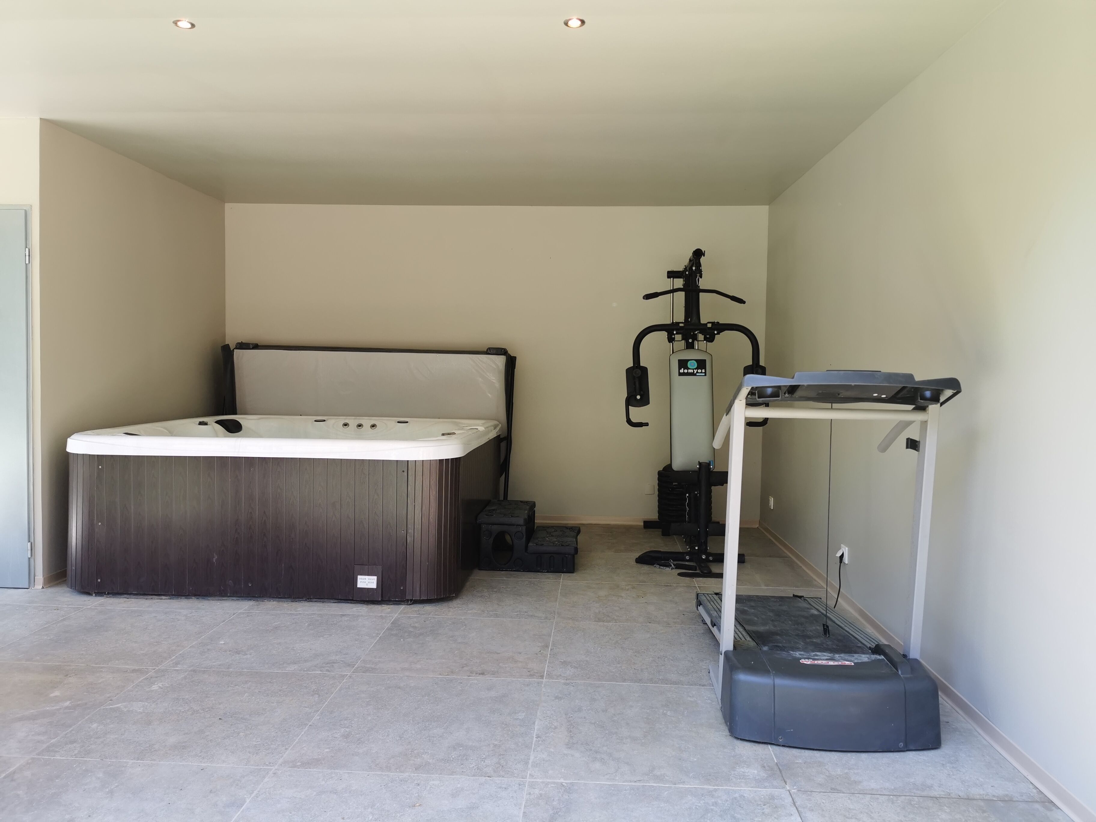 Una habitación con jacuzzi, equipo de ejercicio y una pequeña mesa.