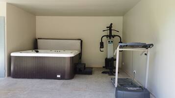 Una habitación con jacuzzi, equipo de ejercicio y una pequeña mesa.