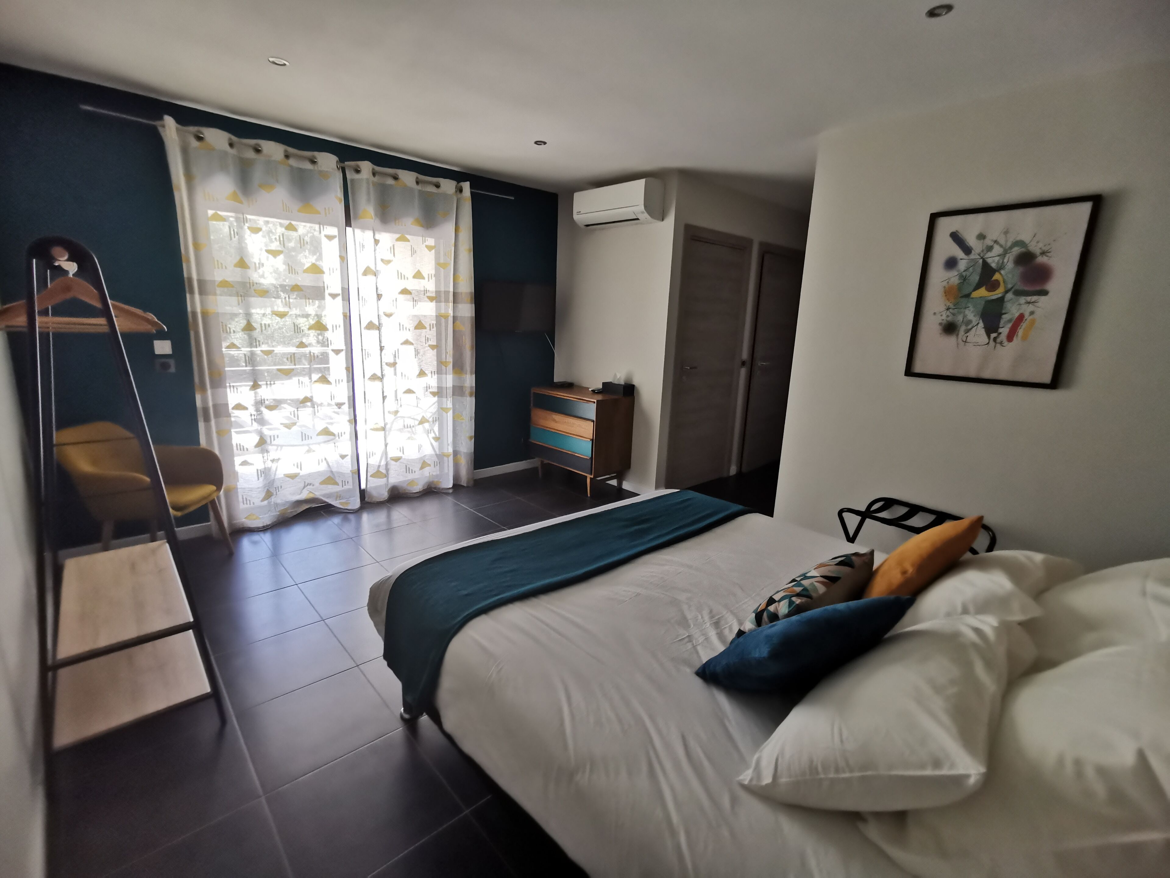 A bedroom with a bed, a wardrobe, a desk, and a hanging chair.