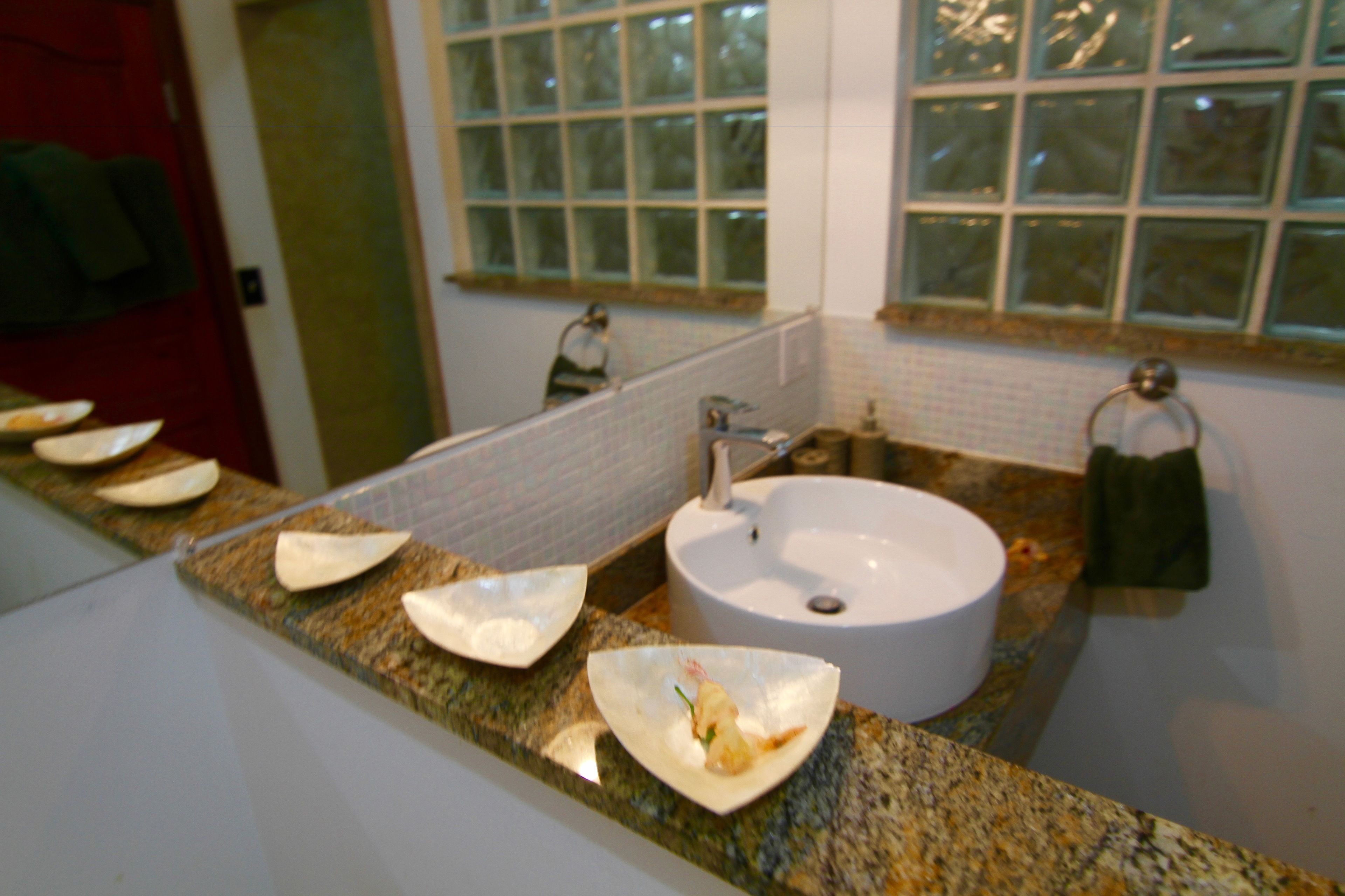 A bathroom with a granite countertop, a white sink, and a mirror.